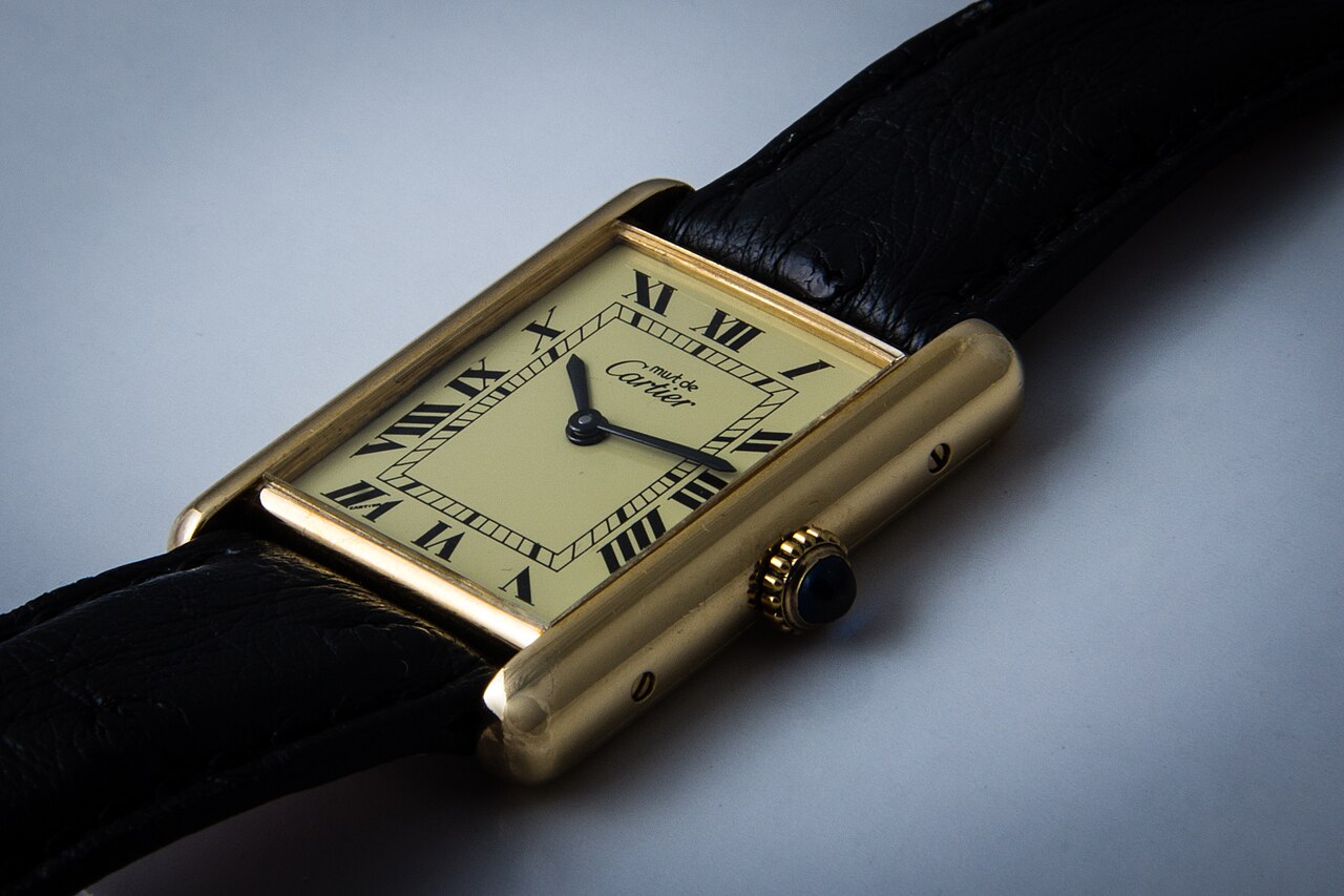 Cartier Tank wristwatch with rectangular case, Roman numeral dial and blue cabochon crown (Must de Cartier Tank shown)